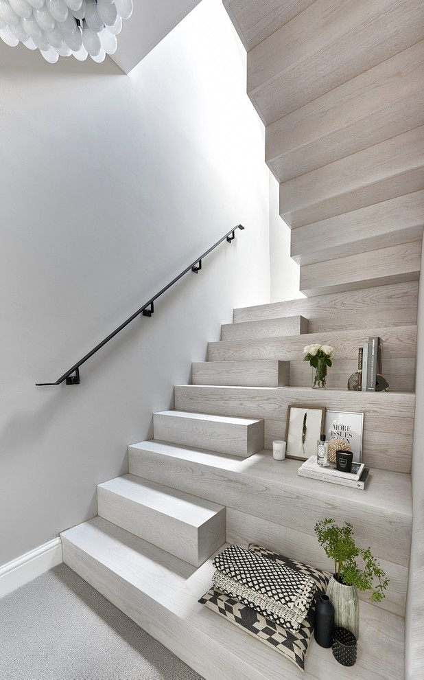 Large contemporary wood curved staircase in Other with metal railing and metal risers.