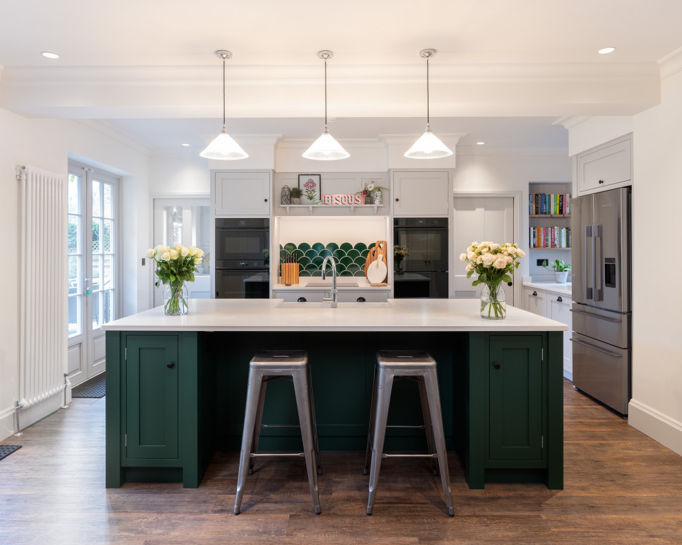 This is an example of a medium sized traditional enclosed kitchen in Other with shaker cabinets, green cabinets, an island, brown floors and white worktops.