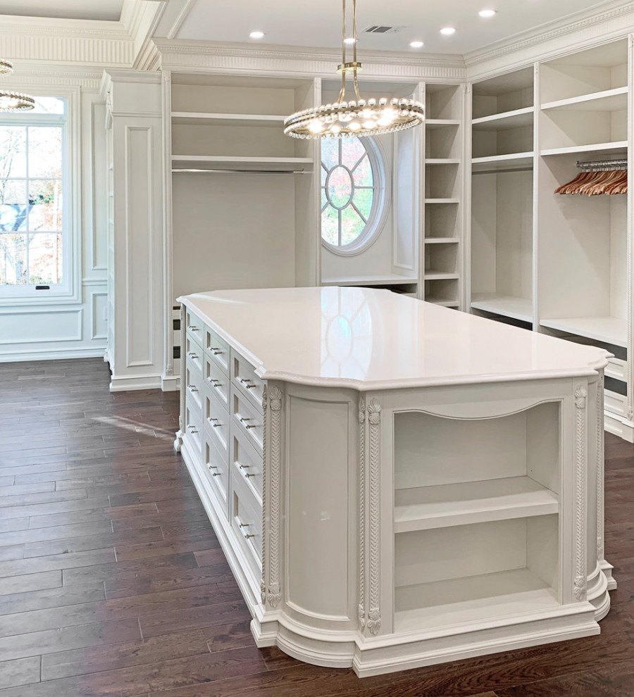 Photo of a large traditional gender-neutral storage and wardrobe in New York with shaker cabinets, white cabinets, dark hardwood floors and brown floor.