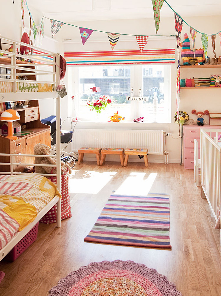 Design ideas for a large scandinavian kids' bedroom for kids 4-10 years old and girls in Stockholm with white walls and light hardwood floors.