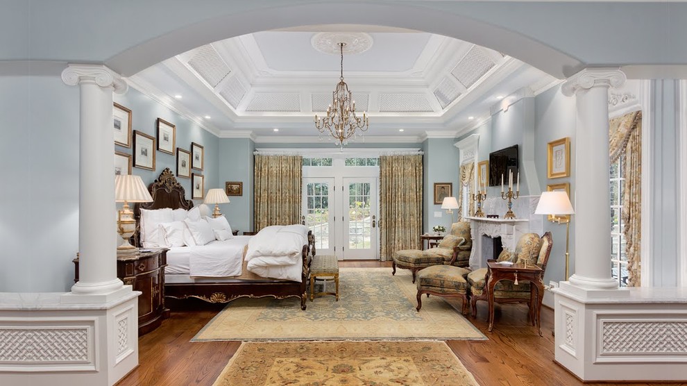 Traditional bedroom in Atlanta with blue walls, medium hardwood floors, a standard fireplace and brown floor.