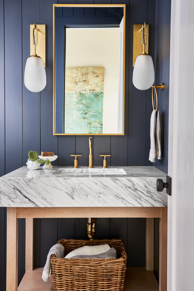 Inspiration for a contemporary powder room in Atlanta with open cabinets, a two-piece toilet, blue walls, light hardwood floors, an undermount sink, marble benchtops, white benchtops, a freestanding vanity, timber and planked wall panelling.