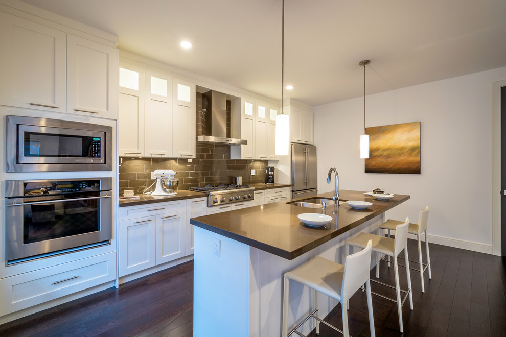 Inspiration for a mid-sized transitional single-wall separate kitchen in DC Metro with a double-bowl sink, shaker cabinets, white cabinets, quartz benchtops, green splashback, glass tile splashback, stainless steel appliances, dark hardwood floors and with island.