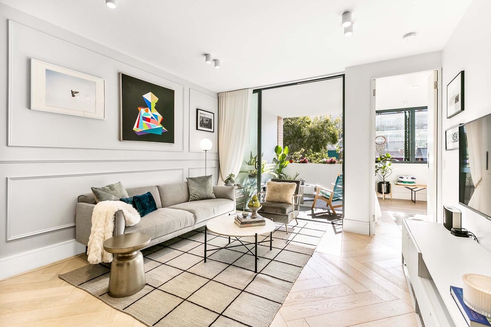 This is an example of a mid-sized contemporary formal open concept living room in Sydney with grey walls, light hardwood floors, no fireplace, beige floor and a wall-mounted tv.