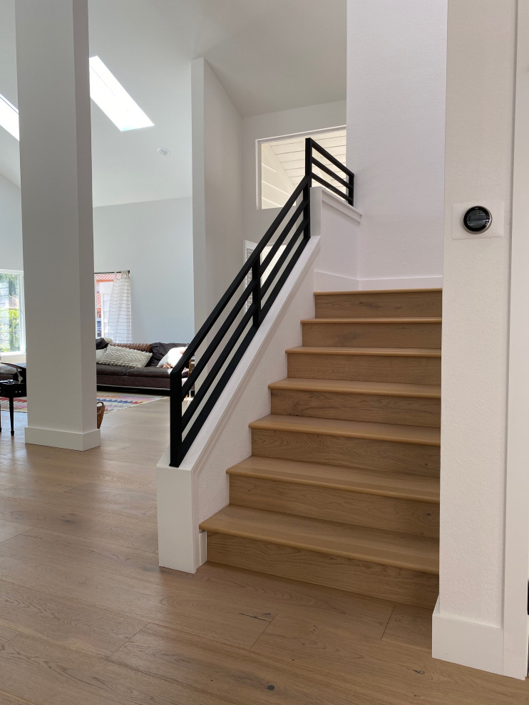 Large scandinavian wood u-shaped staircase in San Diego with wood risers and metal railing.