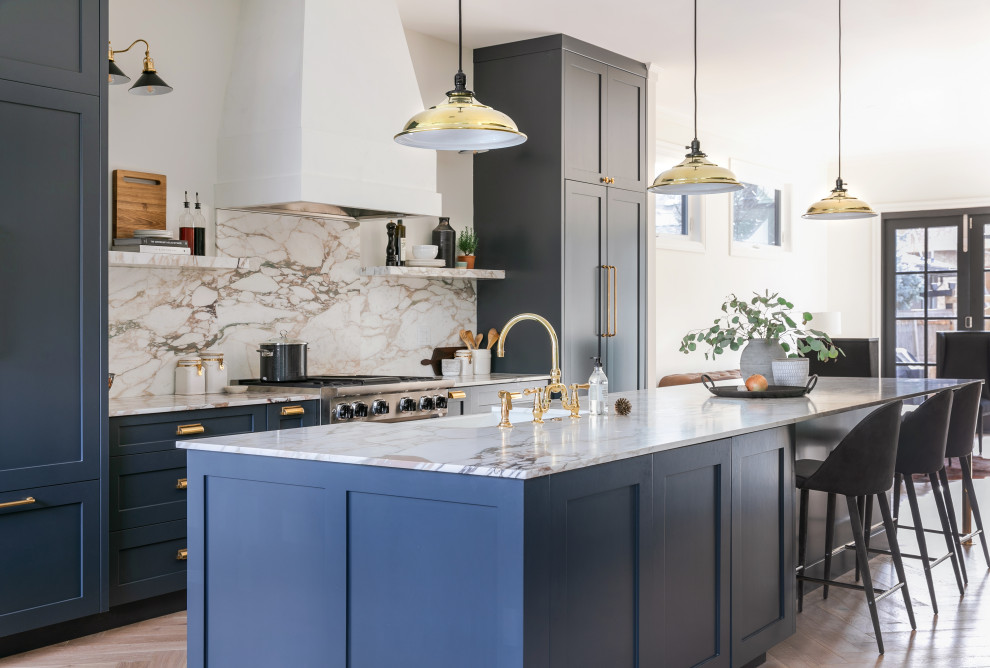 Inspiration for a mid-sized transitional galley open plan kitchen in Calgary with a double-bowl sink, shaker cabinets, blue cabinets, marble benchtops, multi-coloured splashback, marble splashback, panelled appliances, light hardwood floors, with island and multi-coloured benchtop.