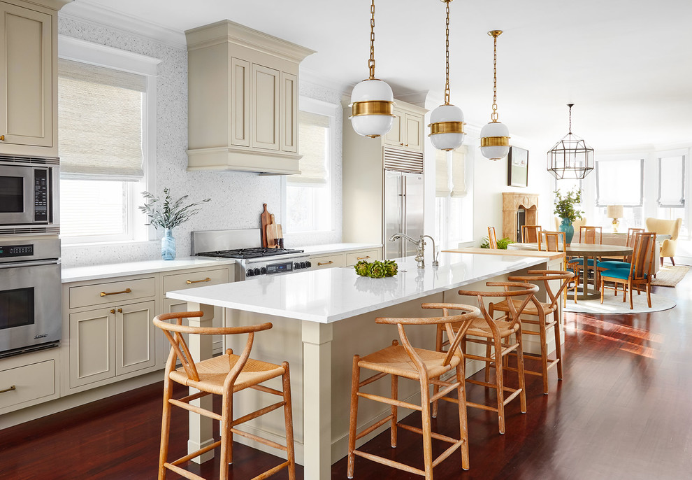 Design ideas for a transitional galley open plan kitchen in Chicago with a farmhouse sink, recessed-panel cabinets, beige cabinets, white splashback, stainless steel appliances, dark hardwood floors, with island, brown floor and white benchtop.