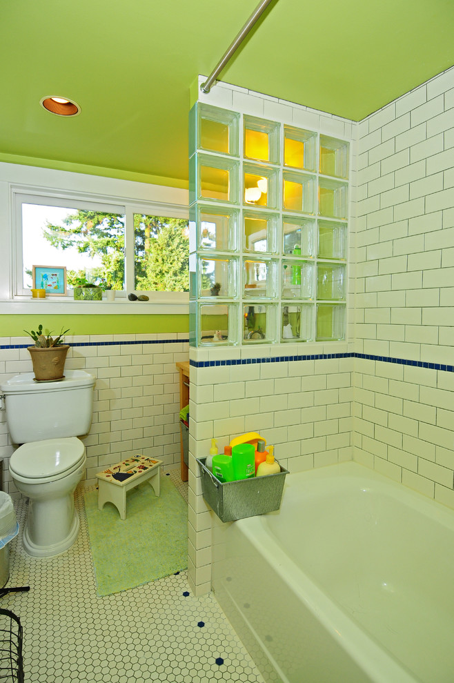 Arts and crafts kids bathroom in Seattle with a drop-in sink, open cabinets, light wood cabinets, wood benchtops, an alcove tub, a shower/bathtub combo, a two-piece toilet, white tile, ceramic tile, green walls and ceramic floors.
