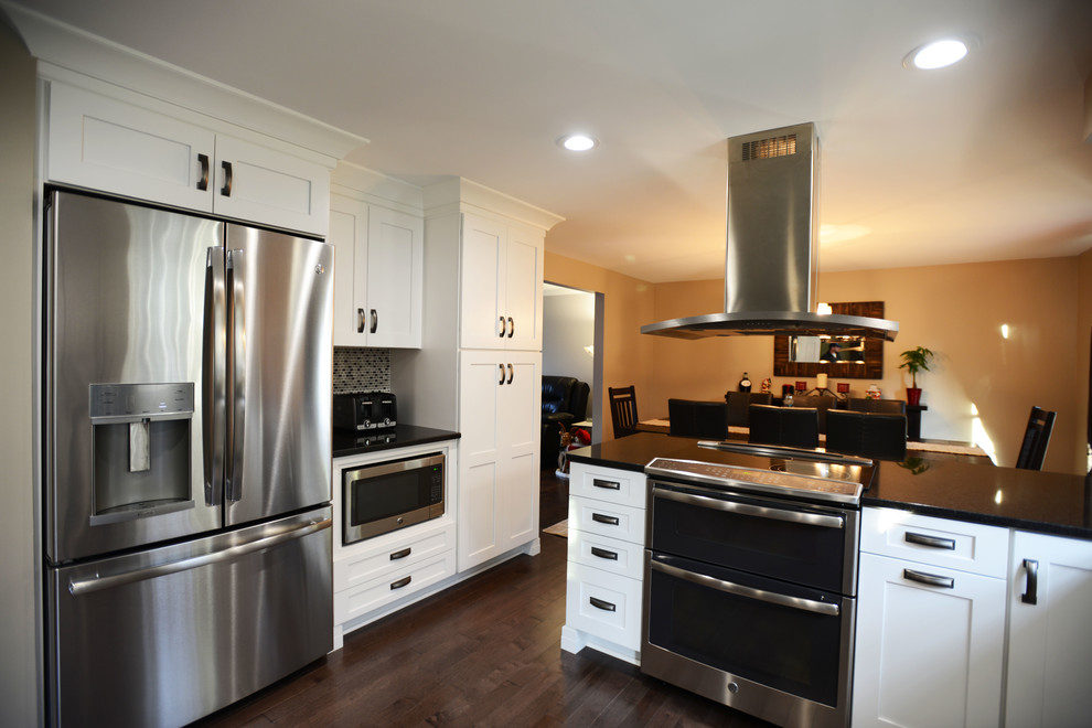 Example of a large transitional u-shaped vinyl floor eat-in kitchen design in Baltimore with a single-bowl sink, shaker cabinets, white cabinets, granite countertops, black backsplash, mosaic tile backsplash, stainless steel appliances and a peninsula