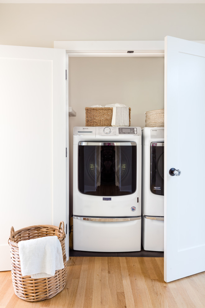 Design ideas for a traditional laundry room in Seattle with light hardwood floors and a side-by-side washer and dryer.