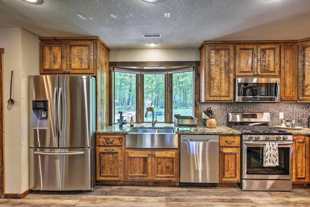Mid-sized mountain style u-shaped vinyl floor and brown floor kitchen pantry photo with a farmhouse sink, raised-panel cabinets, distressed cabinets, granite countertops, gray backsplash, stone tile backsplash, stainless steel appliances, an island and multicolored countertops
