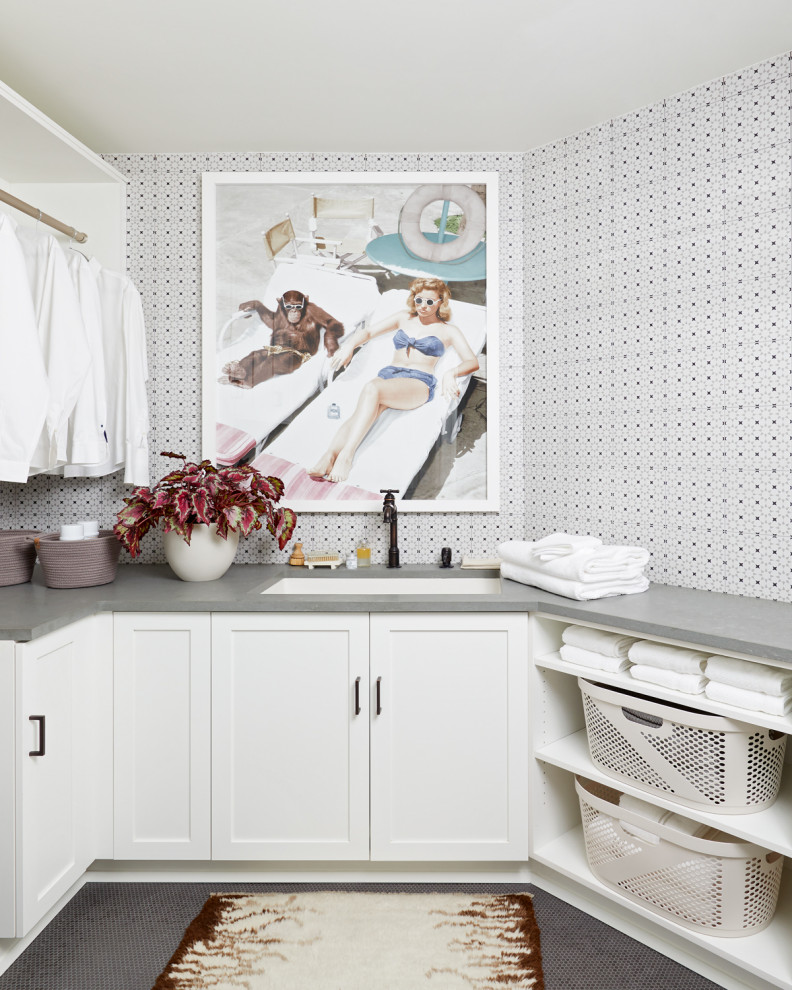 Design ideas for a transitional u-shaped laundry room in New York with an undermount sink, shaker cabinets, white cabinets, black floor, grey benchtop and wallpaper.