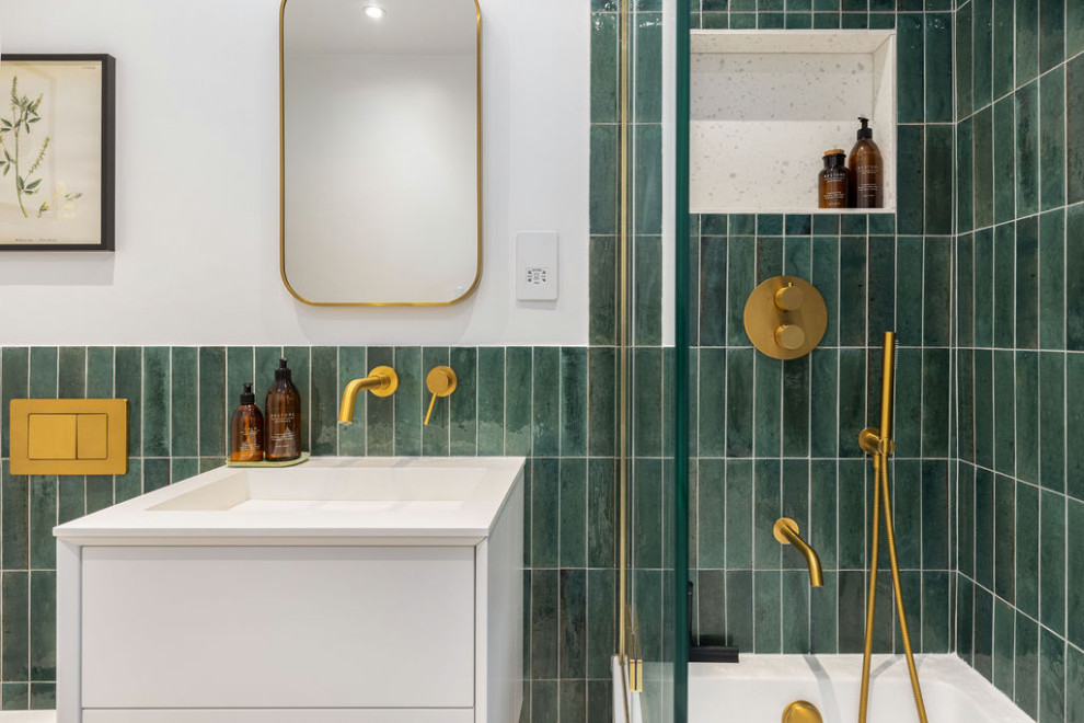 This is an example of a large midcentury bathroom in Hampshire with flat-panel cabinets, white cabinets, a built-in bath, a shower/bath combination, a one-piece toilet, green tiles, matchstick tiles, white walls, a wall-mounted sink, multi-coloured floors, an open shower, a single sink and a floating vanity unit.