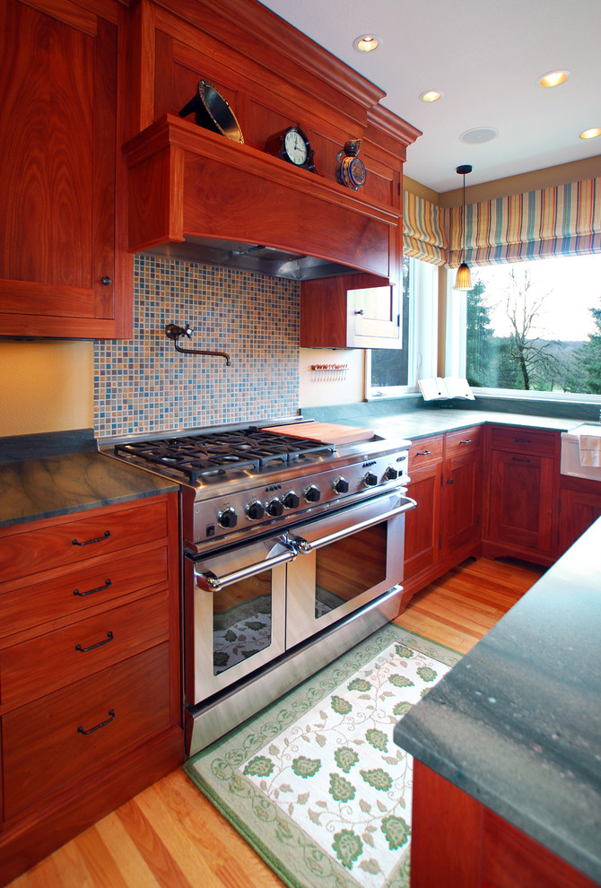 Inspiration for a large traditional l-shaped eat-in kitchen in Portland with an undermount sink, shaker cabinets, medium wood cabinets, granite benchtops, multi-coloured splashback, mosaic tile splashback, stainless steel appliances, light hardwood floors and with island.