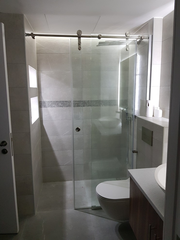 Design ideas for a small modern master bathroom in Other with flat-panel cabinets, brown cabinets, a curbless shower, a wall-mount toilet, gray tile, ceramic tile, grey walls, ceramic floors, a console sink, engineered quartz benchtops and grey floor.