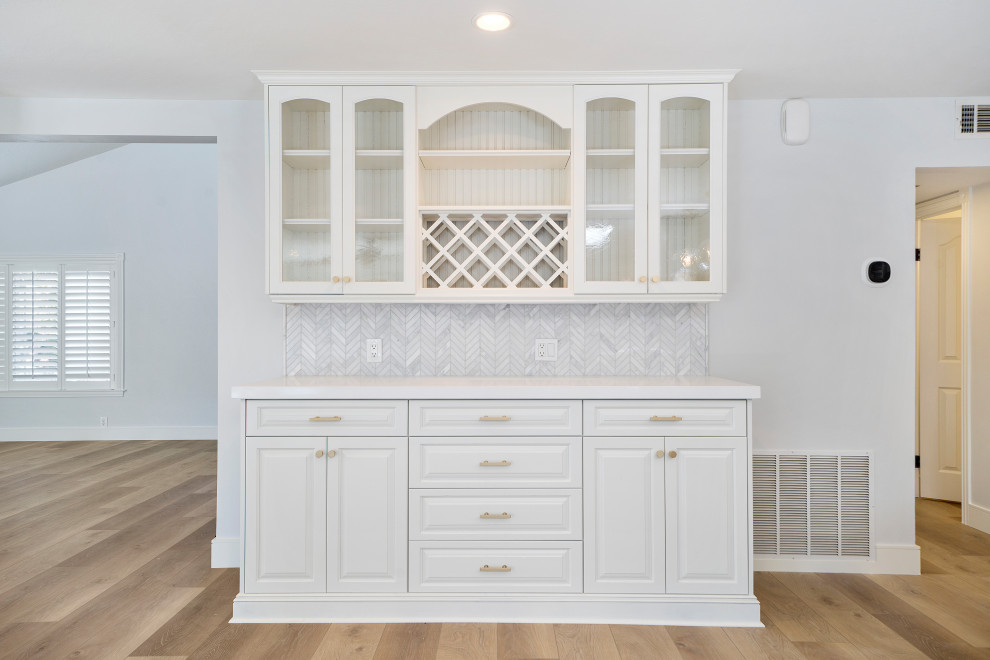 Inspiration for a mid-sized transitional laminate floor and brown floor eat-in kitchen remodel in Orange County with an undermount sink, shaker cabinets, blue cabinets, quartz countertops, white backsplash, mosaic tile backsplash, stainless steel appliances, an island and white countertops