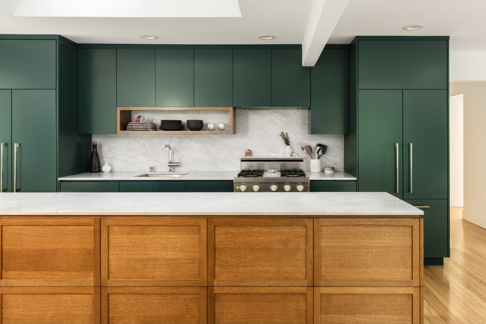 This is an example of a transitional galley kitchen in Seattle with an undermount sink, shaker cabinets, green cabinets, marble benchtops, multi-coloured splashback, marble splashback, panelled appliances, medium hardwood floors, with island, brown floor and multi-coloured benchtop.