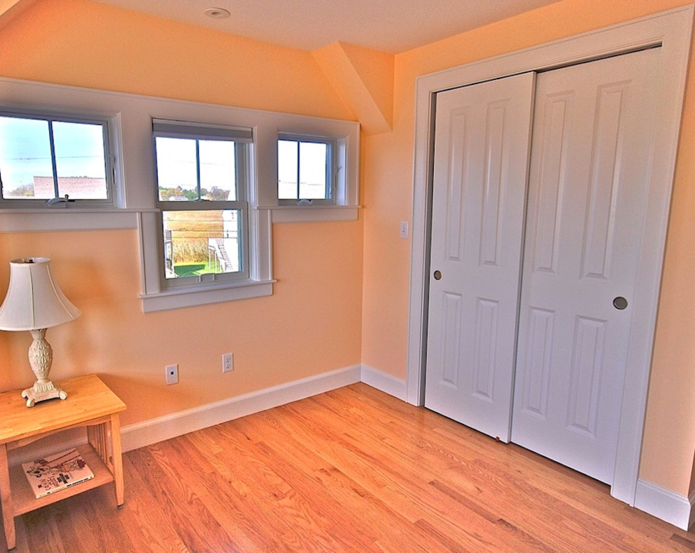 Mid-sized guest bedroom in Portland Maine with yellow walls, medium hardwood floors and no fireplace.