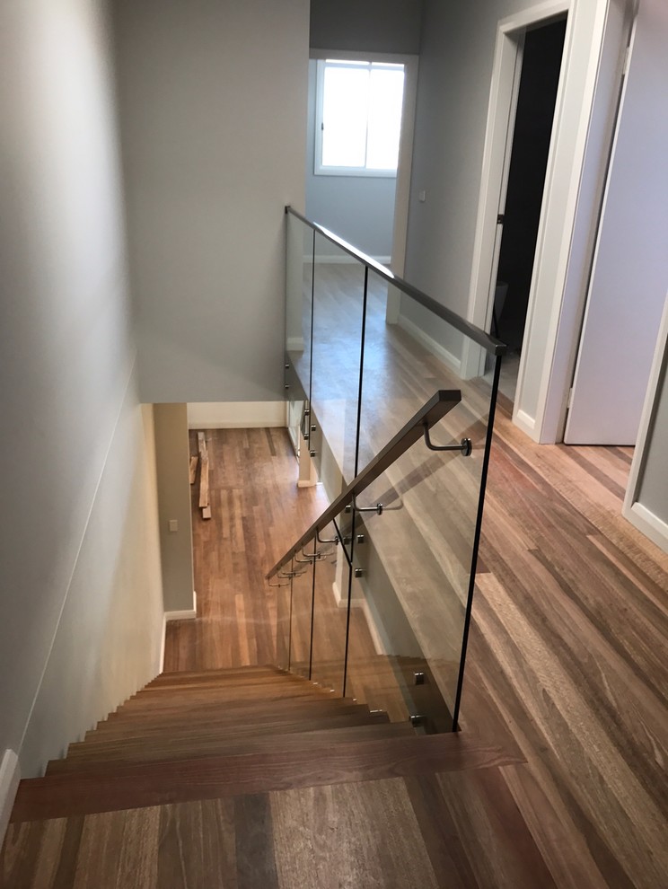 Photo of a mid-sized contemporary wood floating staircase in Sydney with open risers and glass railing.