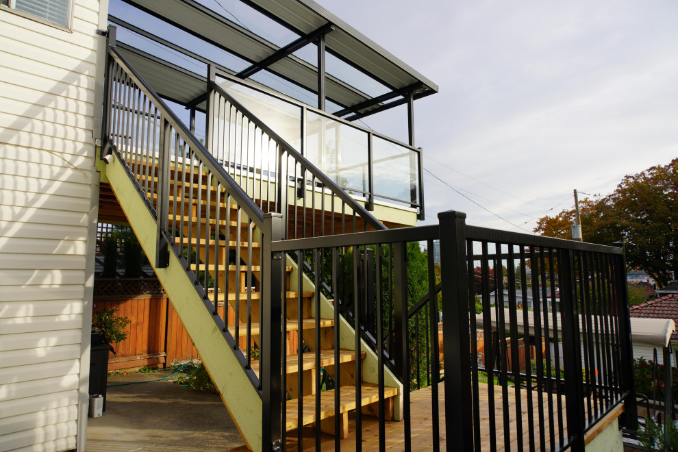 Inspiration for a mid-sized contemporary backyard and first floor deck in Vancouver with an awning and glass railing.