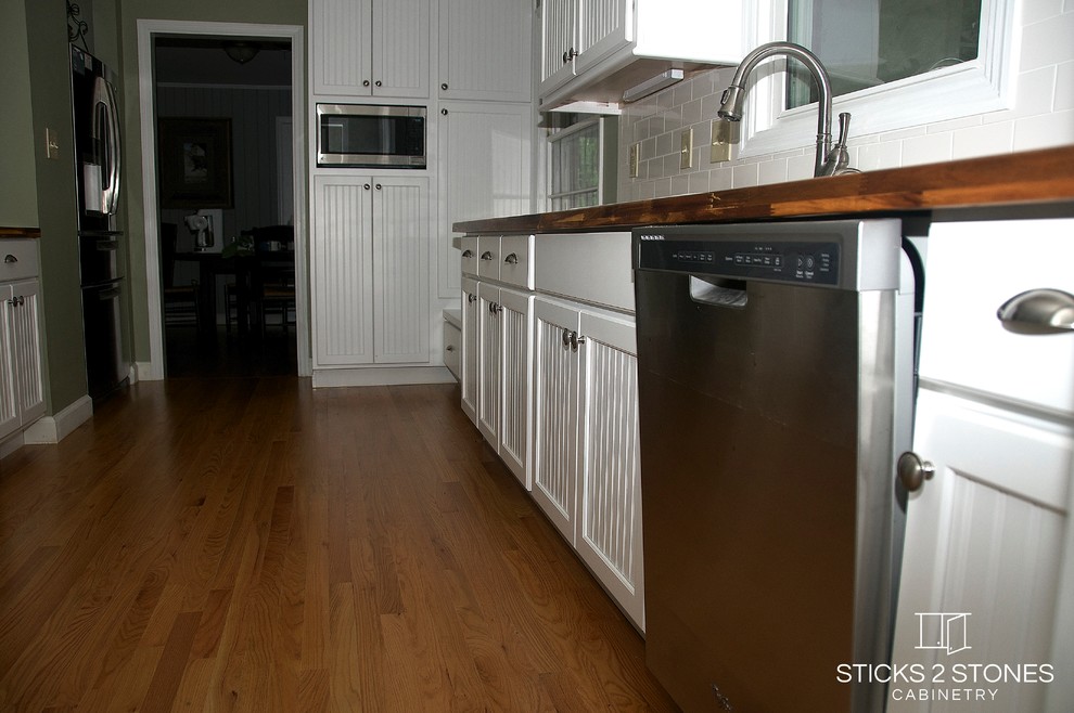 Inspiration for a small timeless galley light wood floor open concept kitchen remodel with a double-bowl sink, shaker cabinets, white cabinets, wood countertops, white backsplash, subway tile backsplash, stainless steel appliances, green walls and a peninsula