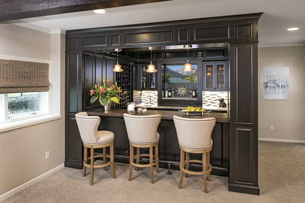 This is an example of a large transitional u-shaped seated home bar in Minneapolis with carpet, raised-panel cabinets, black cabinets, wood benchtops, multi-coloured splashback, matchstick tile splashback, beige floor and an undermount sink.