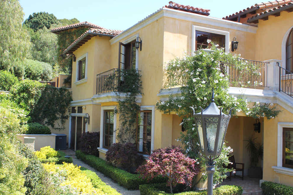 Large mediterranean two-storey stucco yellow exterior in Santa Barbara with a hip roof.