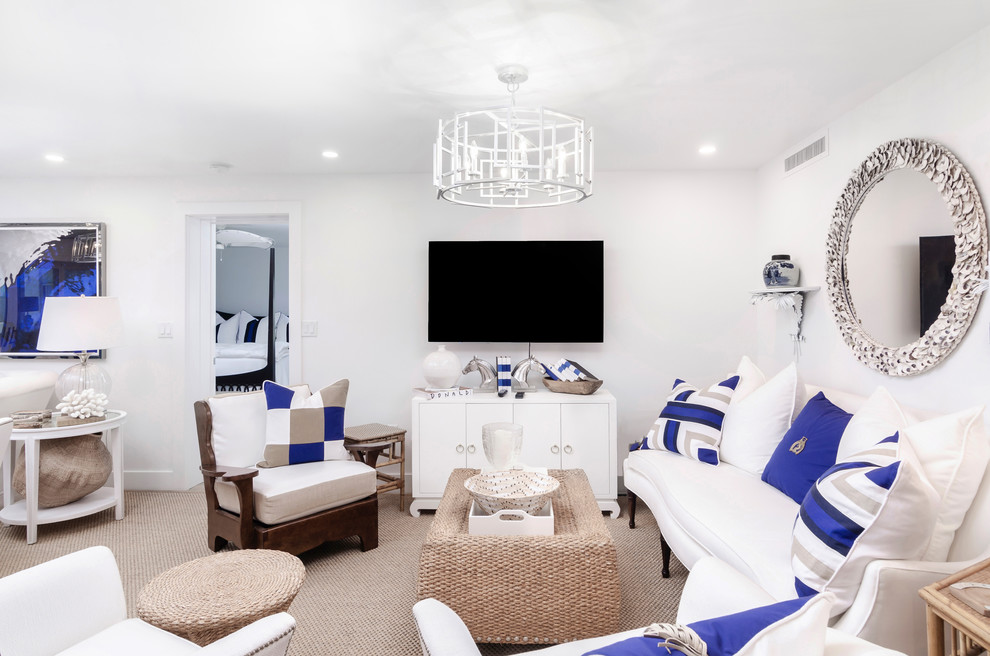 This is an example of a mid-sized beach style open concept family room in Miami with white walls, carpet, no fireplace, a wall-mounted tv and beige floor.