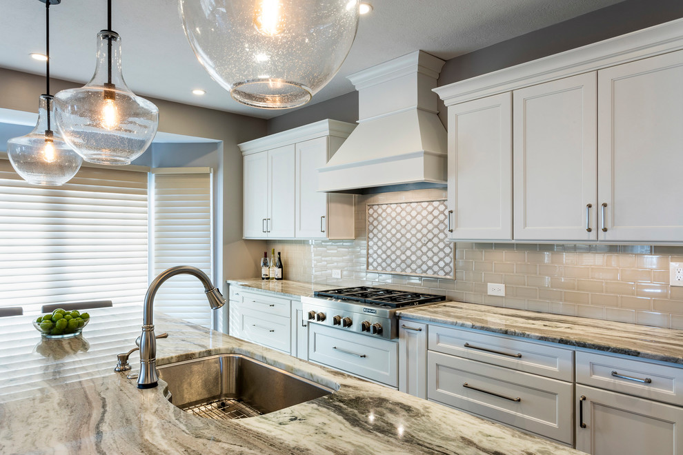 Example of a large transitional vinyl floor and brown floor kitchen design with an undermount sink, recessed-panel cabinets, white cabinets, granite countertops, beige backsplash, ceramic backsplash, stainless steel appliances and an island