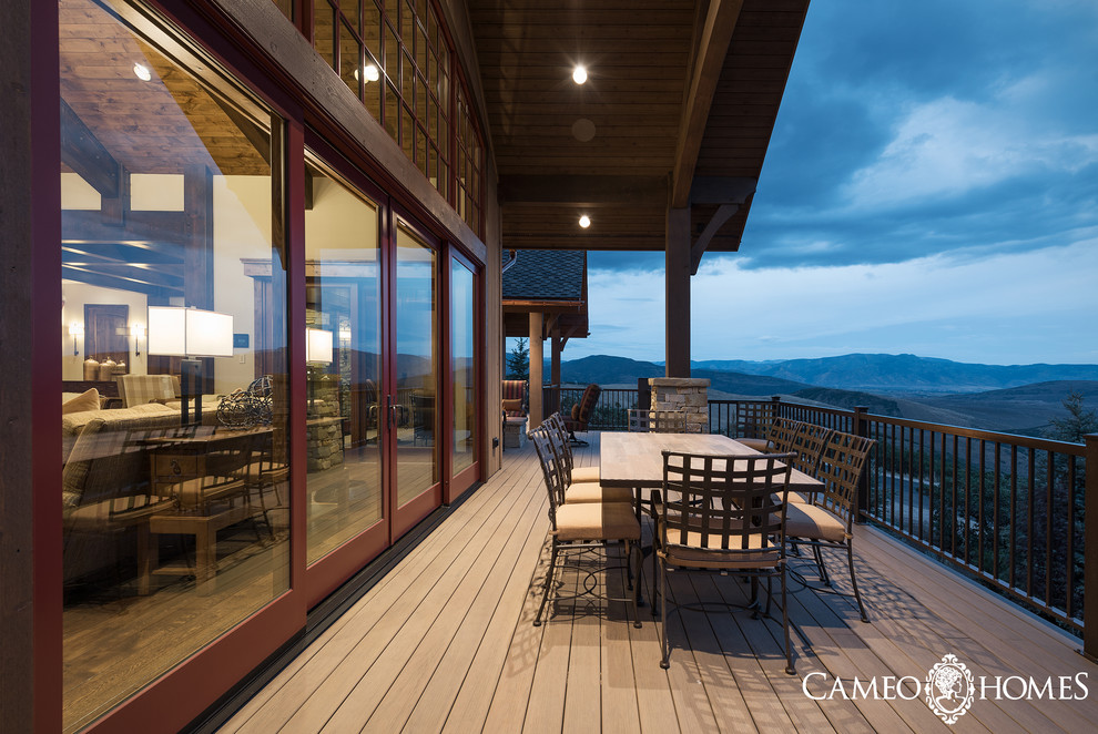 This is an example of an expansive country backyard deck in Salt Lake City with an outdoor kitchen and a roof extension.
