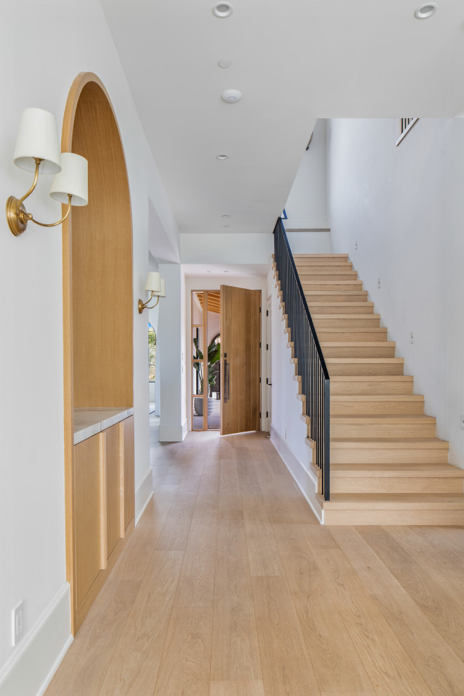 Mid-sized mediterranean foyer in Los Angeles with white walls, light hardwood floors, a single front door, a light wood front door and beige floor.