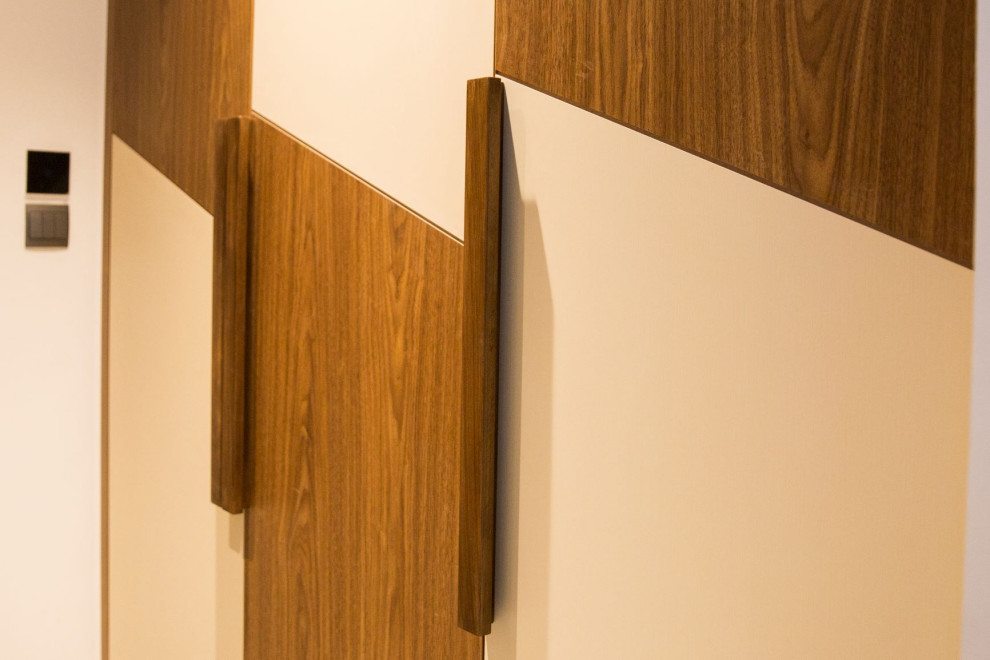 Exemple d'une grande armoire encastrée tendance en bois clair neutre avec un placard à porte plane.