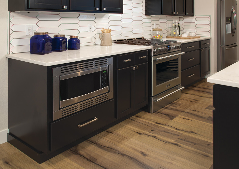 Minimalist kitchen photo with shaker cabinets, white backsplash, stainless steel appliances and an island