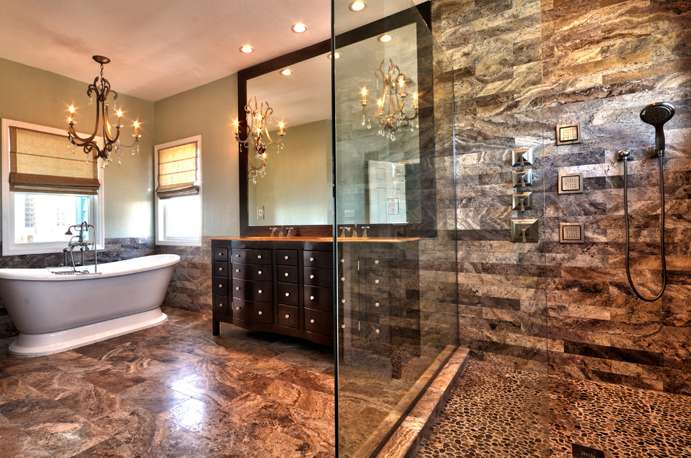Large contemporary master bathroom in Tampa with furniture-like cabinets, dark wood cabinets, a freestanding tub, a corner shower, a two-piece toilet, multi-coloured tile, pebble tile, green walls, travertine floors, a console sink and granite benchtops.
