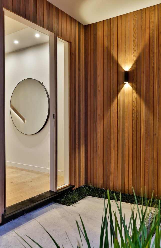 Photo of a mid-sized contemporary foyer in Auckland with white walls, medium hardwood floors, a single front door and beige floor.