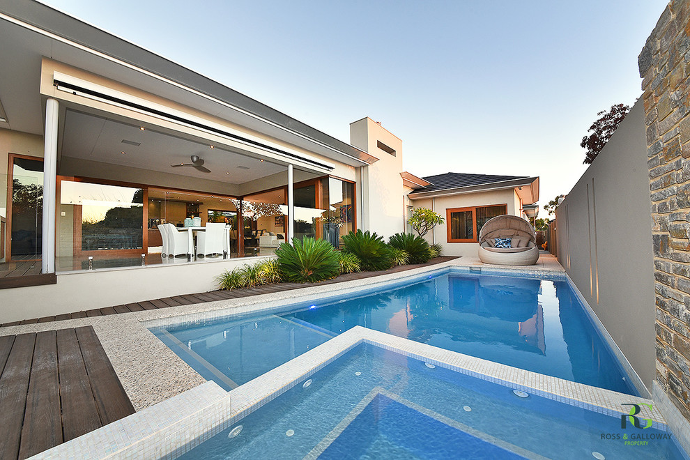 This is an example of a mid-sized modern side yard custom-shaped lap pool in Perth with a hot tub and decking.