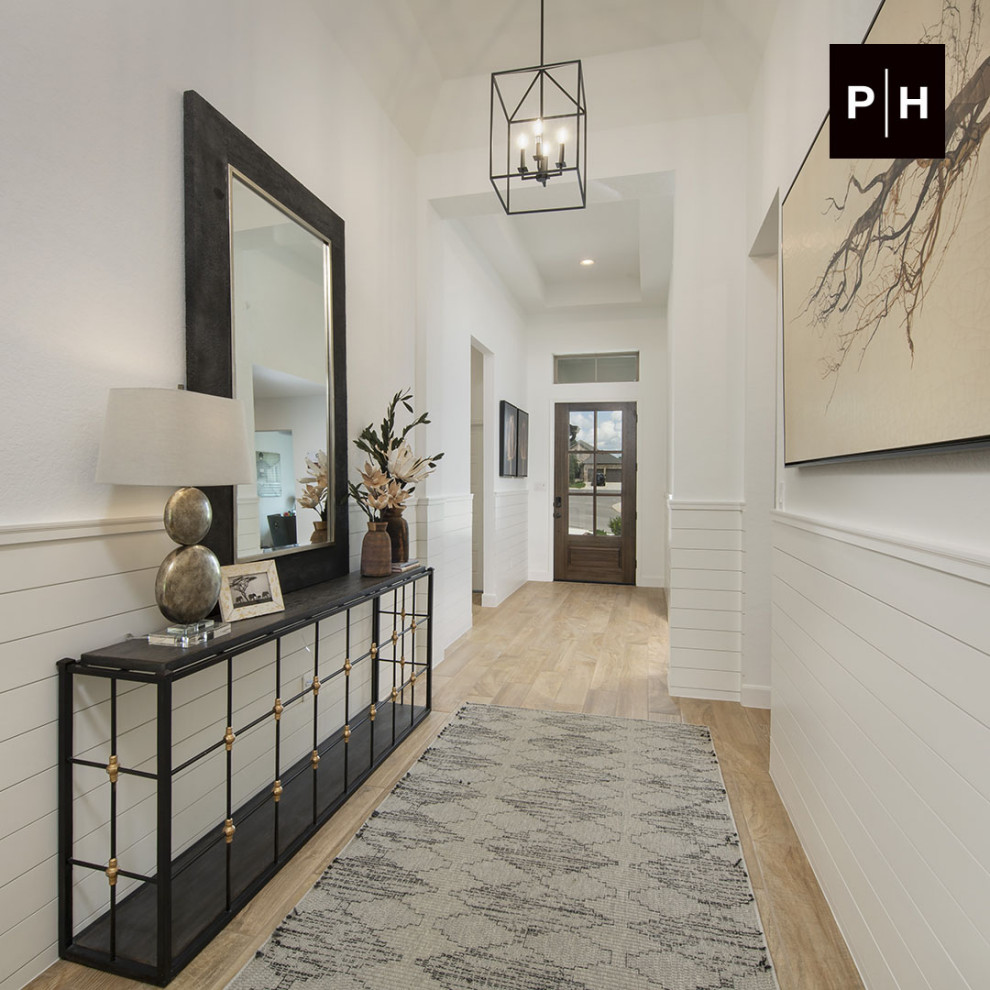 Diseño de hall abovedado con paredes blancas, suelo de madera clara, puerta simple, puerta de madera en tonos medios y machihembrado