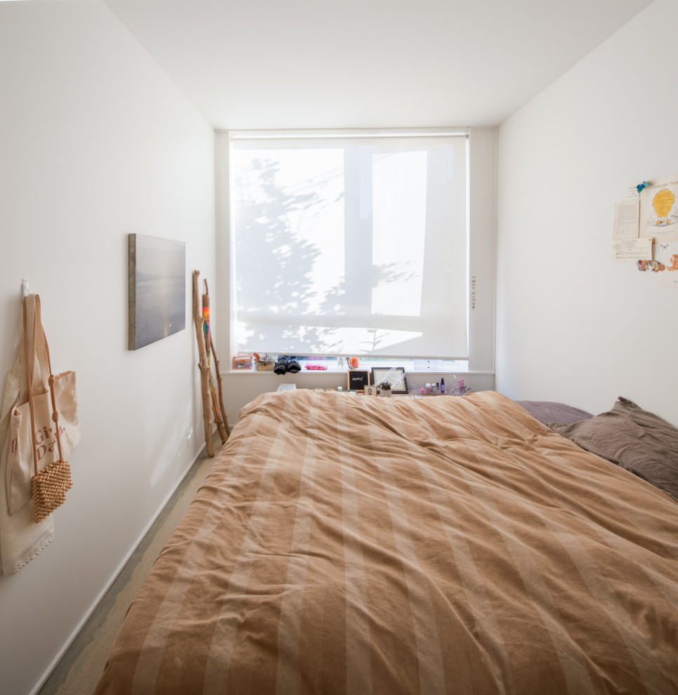Imagen de dormitorio minimalista con paredes blancas y suelo de cemento