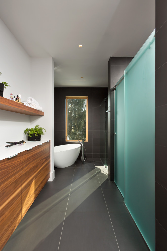 Inspiration for a large modern master bathroom in New York with flat-panel cabinets, medium wood cabinets, solid surface benchtops, a floating vanity, a freestanding tub, a double shower, white walls, porcelain floors, grey floor, a sliding shower screen, white benchtops, a niche and a single vanity.