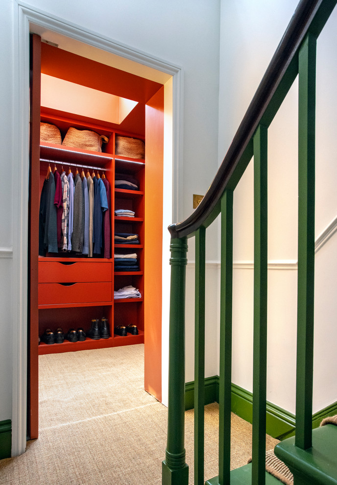Inspiration for a mid-sized contemporary gender-neutral walk-in wardrobe in London with flat-panel cabinets, red cabinets, carpet and beige floor.