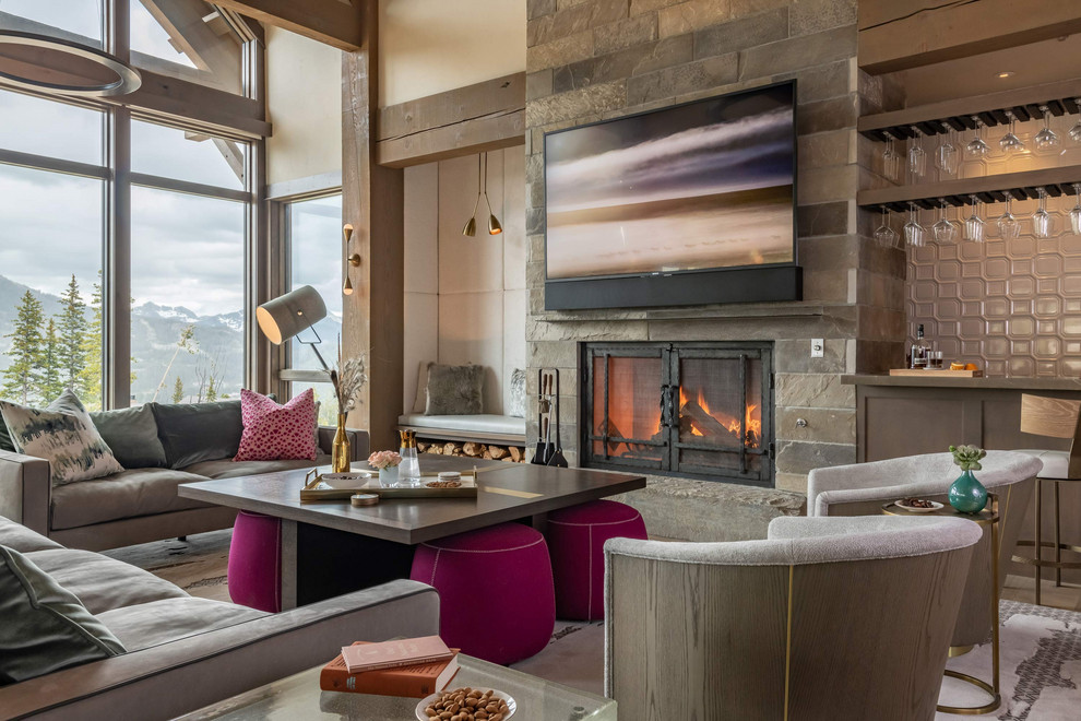 Photo of a country open concept family room in Other with a home bar, beige walls, a standard fireplace, a stone fireplace surround and a wall-mounted tv.