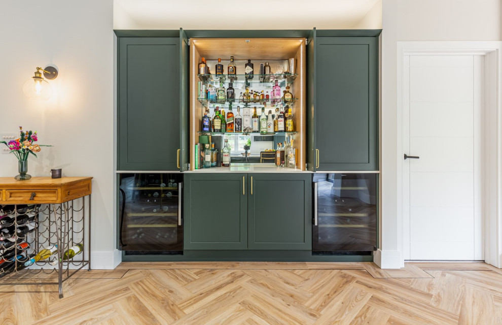 Design ideas for a large modern single-wall home bar in Other with shaker cabinets, green cabinets, light hardwood floors, brown floor and white benchtop.