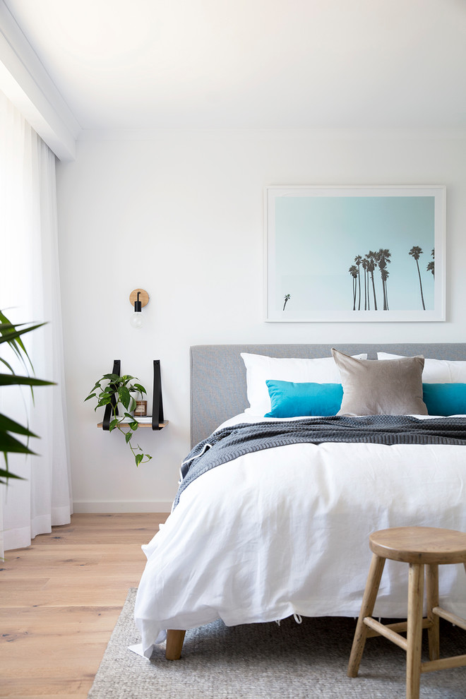 Design ideas for a beach style bedroom in Brisbane with white walls and light hardwood floors.