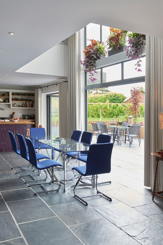 This is an example of a large contemporary open plan dining in Wiltshire with white walls, slate floors and black floor.