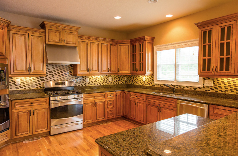 Kitchen - medium tone wood floor and brown floor kitchen idea with a double-bowl sink, glass-front cabinets, medium tone wood cabinets, granite countertops, black backsplash, ceramic backsplash, stainless steel appliances, an island and brown countertops