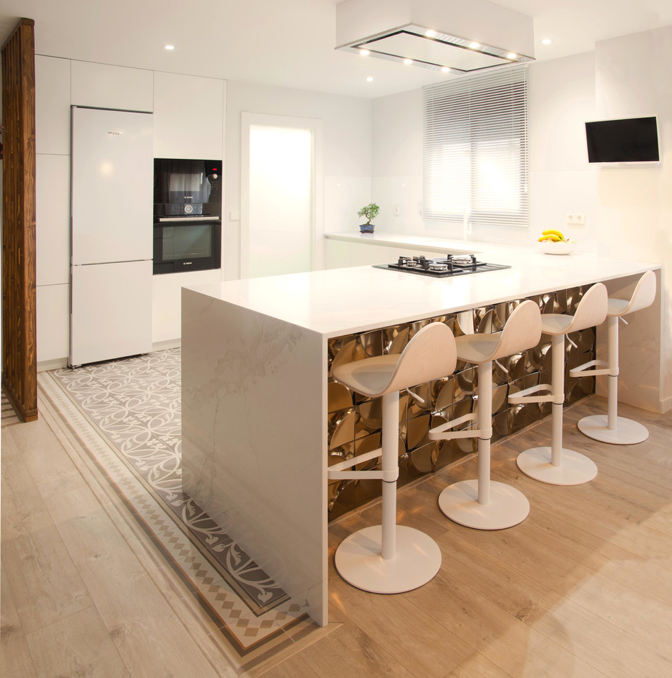 Design ideas for a contemporary u-shaped kitchen in Valencia with quartz benchtops, a peninsula, white benchtop, flat-panel cabinets, white cabinets, white splashback, black appliances and grey floor.