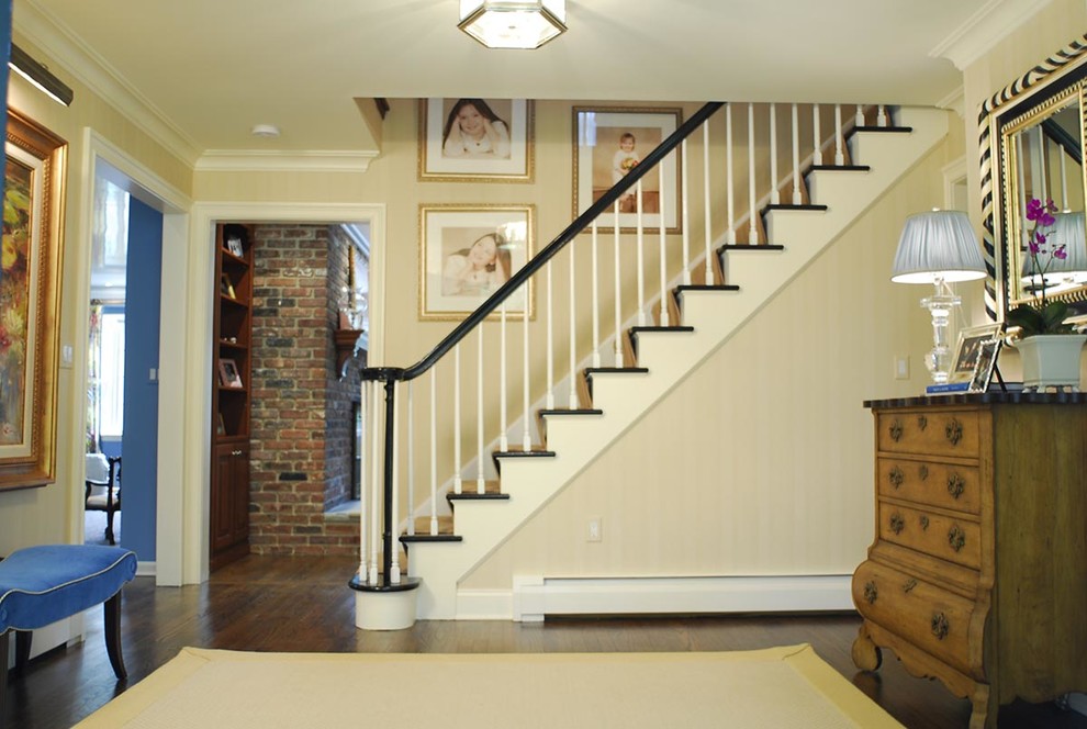 This is an example of a large traditional foyer in New York with dark hardwood floors, a single front door and a black front door.