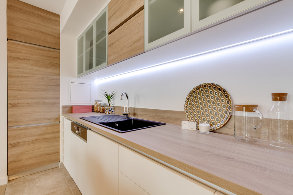 Design ideas for a mid-sized scandinavian u-shaped eat-in kitchen in Paris with an integrated sink, flat-panel cabinets, light wood cabinets, wood benchtops, white splashback, panelled appliances, travertine floors, no island and beige floor.