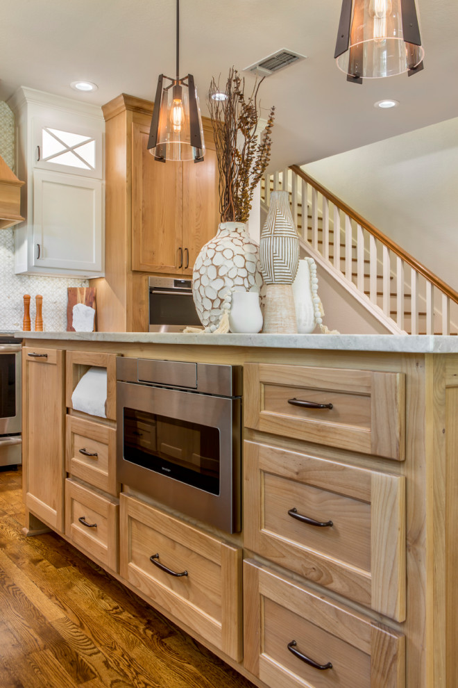 Example of a large farmhouse l-shaped medium tone wood floor and brown floor enclosed kitchen design in Other with a farmhouse sink, shaker cabinets, white cabinets, quartzite countertops, gray backsplash, mosaic tile backsplash, stainless steel appliances, an island and gray countertops