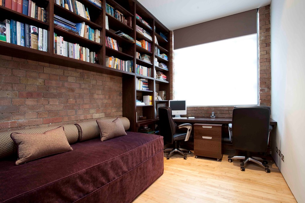 Contemporary home office in London with light hardwood floors, no fireplace and a built-in desk.